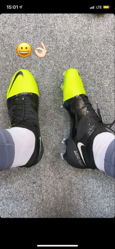 a pair of black and yellow shoes sitting on top of a gray carpet next to an orange ball