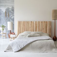 a bed with white linens and wooden headboard next to two lamps on either side