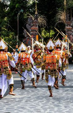 a group of men in uniform marching down the street with sticks and poles around their necks