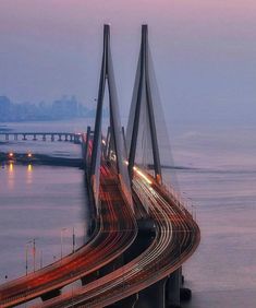 an image of a bridge that is going over the water at night with cars driving on it