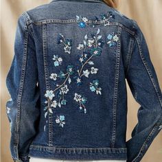 a woman wearing a jean jacket with flowers on it