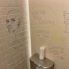 a bathroom stall with two toilet paper dispensers and drawings on the wall