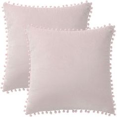 two pink pillows with pom - poms on the sides and one in white