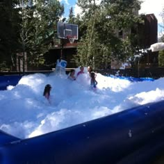 two children playing in an inflatable pool with snow on the ground and trees behind them