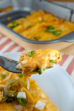 a spoon full of food is being lifted from a casserole dish with cheese and green onions