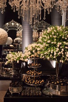 a table topped with lots of desserts and vases filled with white tulips