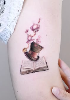 a woman's arm with an open book and hat on it