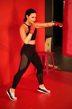 a woman in black sports bra top and leggings with red boxing gloves on