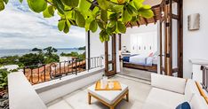 a living room with white furniture and a balcony overlooking the ocean