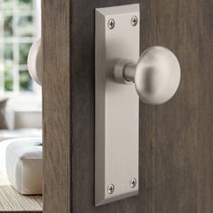 a door handle on a wooden door with a white window in the backround