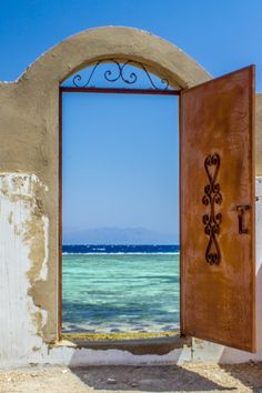 an open door leading to the ocean with a blue sky and water in the background