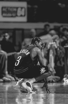 a basketball player sitting on the floor in front of an audience with his head down