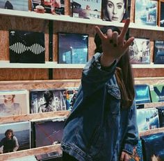 a person making the v sign with their hand in front of record store shelves filled with records