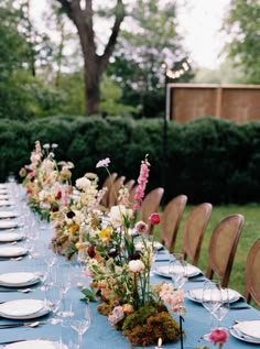 a long table is set with plates and place settings for an outdoor dinner party in the garden