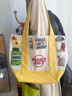 a yellow and white tote bag hanging from a hook