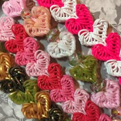 there are many small crocheted hearts on the table with ribbons attached to them