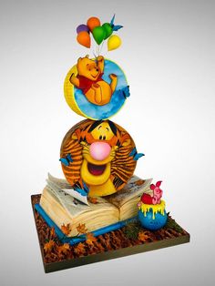 winnie the pooh birthday cake on top of an open book with balloons floating above it