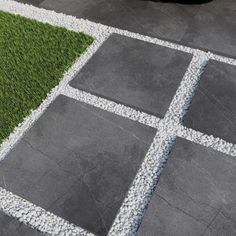 a black car is parked in front of some grass and gravel squares on the ground