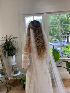 the back of a bride's wedding dress, with her veil draped over her head