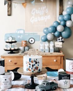 a table topped with a cake covered in frosting next to balloons and other decorations