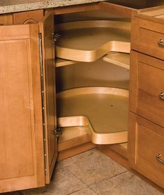 an open cabinet in a kitchen with marble counter tops