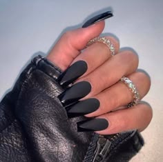 a woman's hand with black stiled nails and ring on her finger, holding a