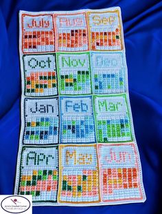 a crocheted blanket with words written in different colors and sizes on it, sitting on a blue cloth