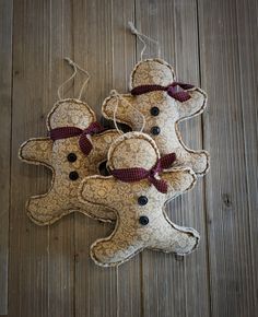 three gingerbread man ornaments hanging on a wooden floor with string and buttons attached to them