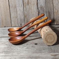 four wooden spoons are lined up next to each other