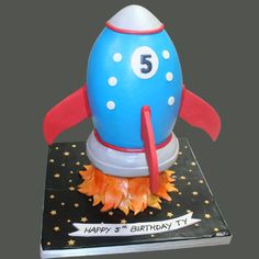 a birthday cake shaped like a rocket ship with the number five on it's side