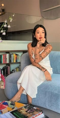 a woman with tattoos sitting on a blue couch