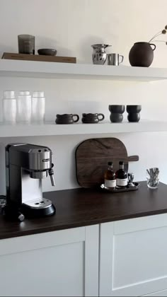 a coffee maker sitting on top of a counter next to some cups and saucers