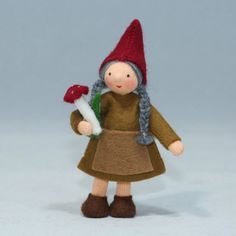 a small doll with a red hat and gray hair holding a green leaf in her hand