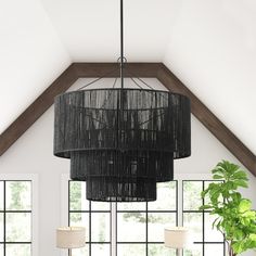 a black chandelier hanging from the ceiling in a living room with large windows