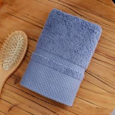 a wooden table topped with two blue towels and a hair brush on top of it