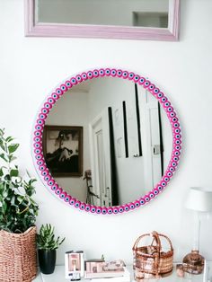 a mirror is hanging on the wall above a table with some plants and other items