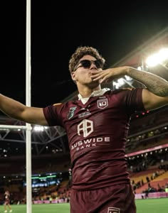 a man in maroon jersey standing next to a flag