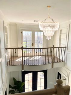 an open staircase leading up to the second floor with chandelier hanging from the ceiling