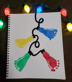 a hand and foot print on a sheet of paper with christmas lights around the edges