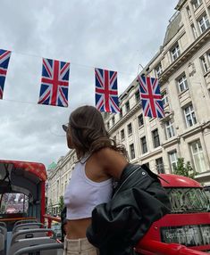 a woman standing in front of a red truck with british flags hanging from it's roof