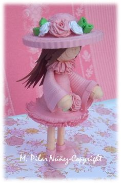 a small doll wearing a pink dress and hat with flowers on it's head