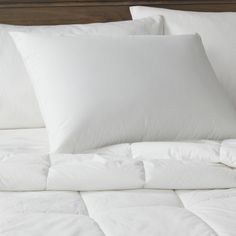 a bed with white sheets and pillows on it