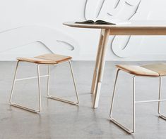 two wooden stools sitting next to a table with an open book on top of it