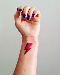 a woman's arm with a red and black lightning bolt tattoo on the wrist