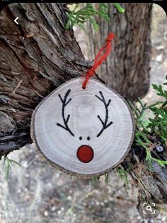 a wooden ornament hanging from a tree with reindeer's face painted on it