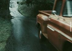 an orange truck driving down a wet road