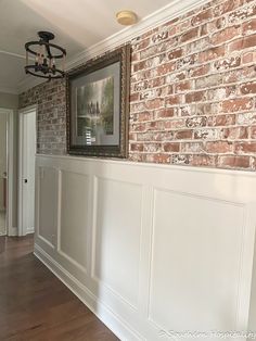 an empty room with brick wall and wood flooring on the walls, along with a chandelier