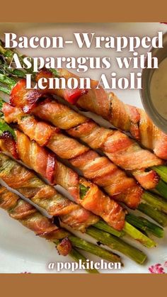 bacon wrapped asparagus with lemon aioli on a white plate next to dipping sauce