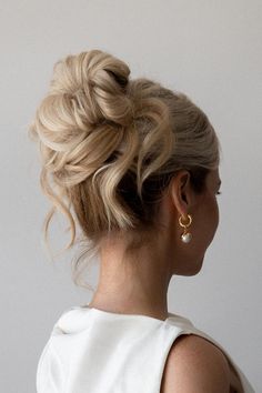 a woman with blonde hair wearing a white dress and gold hoop earrings on her head