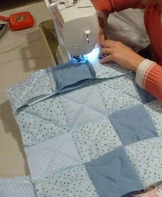 a woman is using a sewing machine to sew something on a piece of cloth